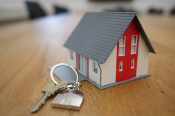 Toy house with red door on desk with set of keys